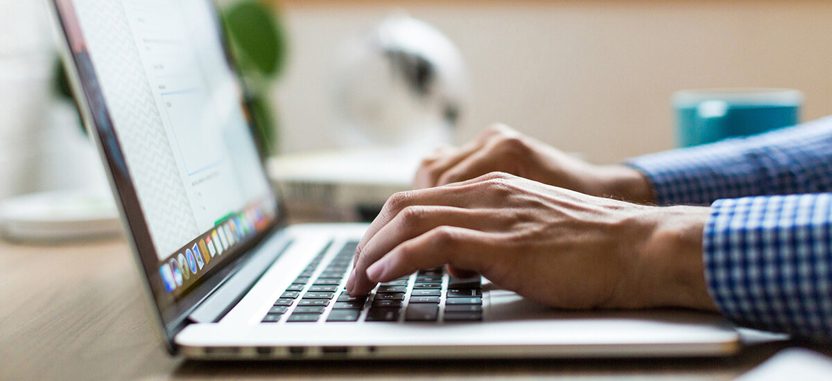 A man’s hands typing on laptop computer, making contact by filling out online form from the Contact Us page of our Web site.