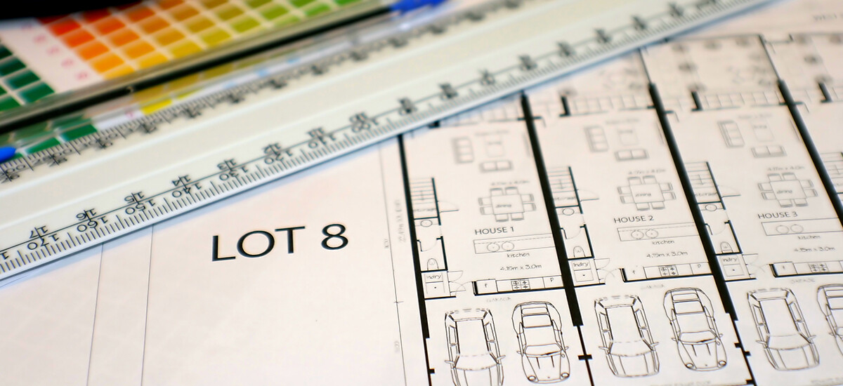 Architectural floor plans of town houses with 2-car double garage, overlaid with blue pen and scale rule. In background is colour selection chart