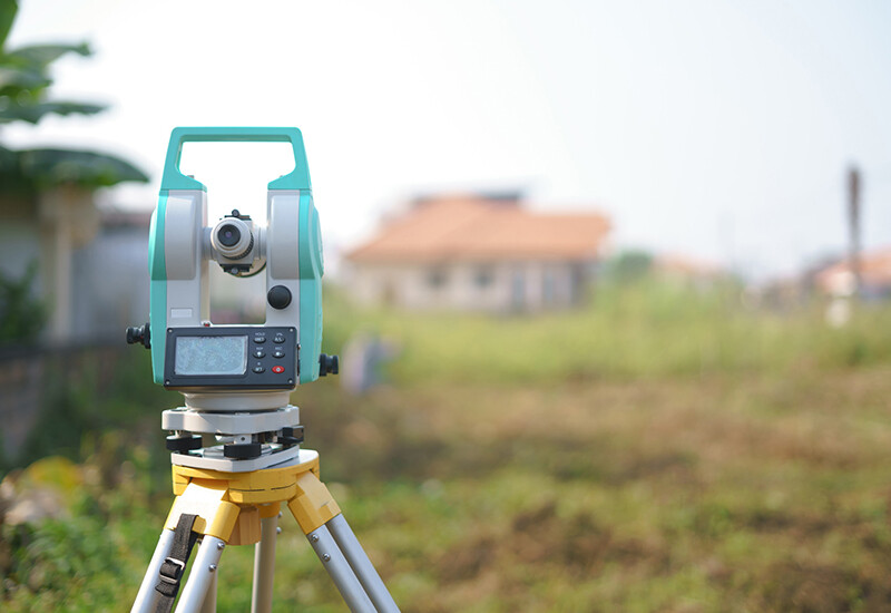 Surveying vacant block of land. Working with a theodolite on a tripod, a surveyor locates the exact position of the boundary, the topographical spot levels and interpolated contours of the site, as well as existing structures, needed especially on a tight site.