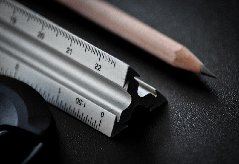 Architects traditional tools of trade, the traditional scale ruler, and sharpened lead pencil on black desk