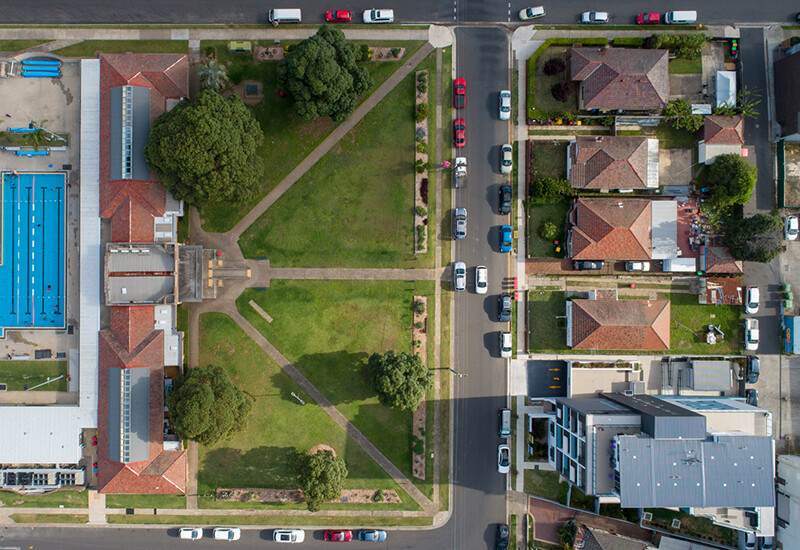 Aerial plan view of local public swimming pool with surveyed paths on park. Subdivided house lots, and new multi-storey residential apartment building